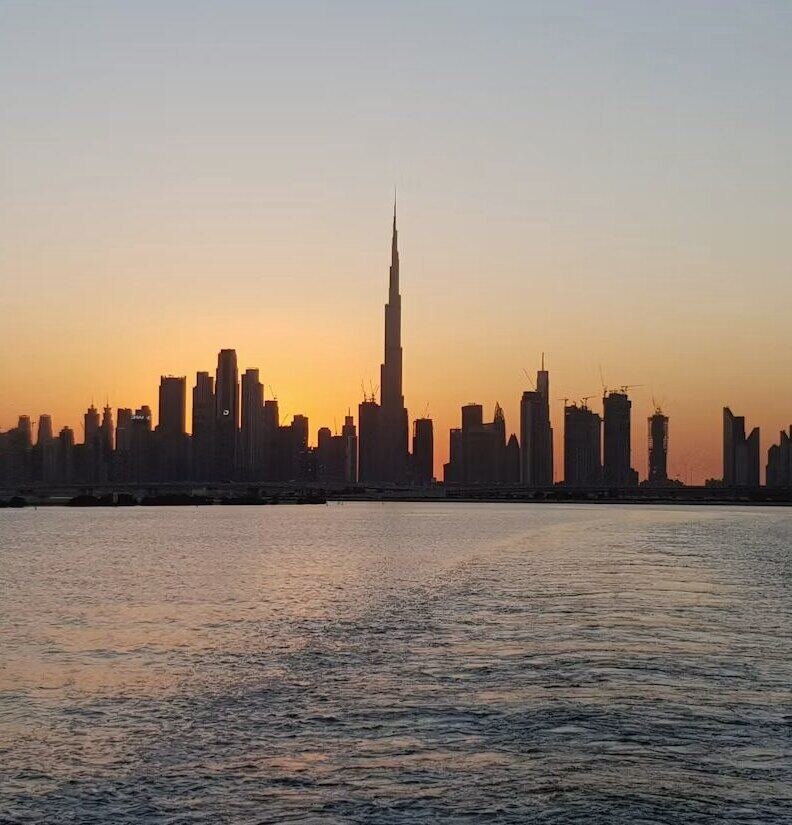 Dubai skyline silhouette across the water at sunset (illustrative photo) – not a photo of Dubai Sports City