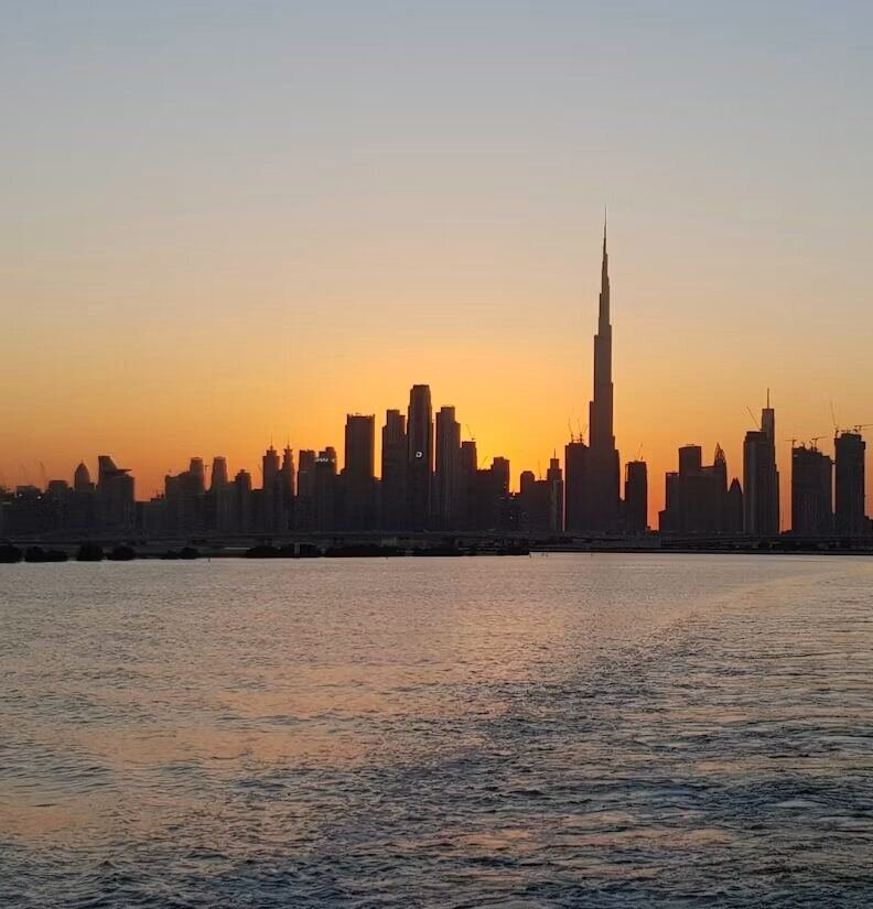 Dubai skyline silhouette across the water at sunset (illustrative photo) – not a photo of International City
